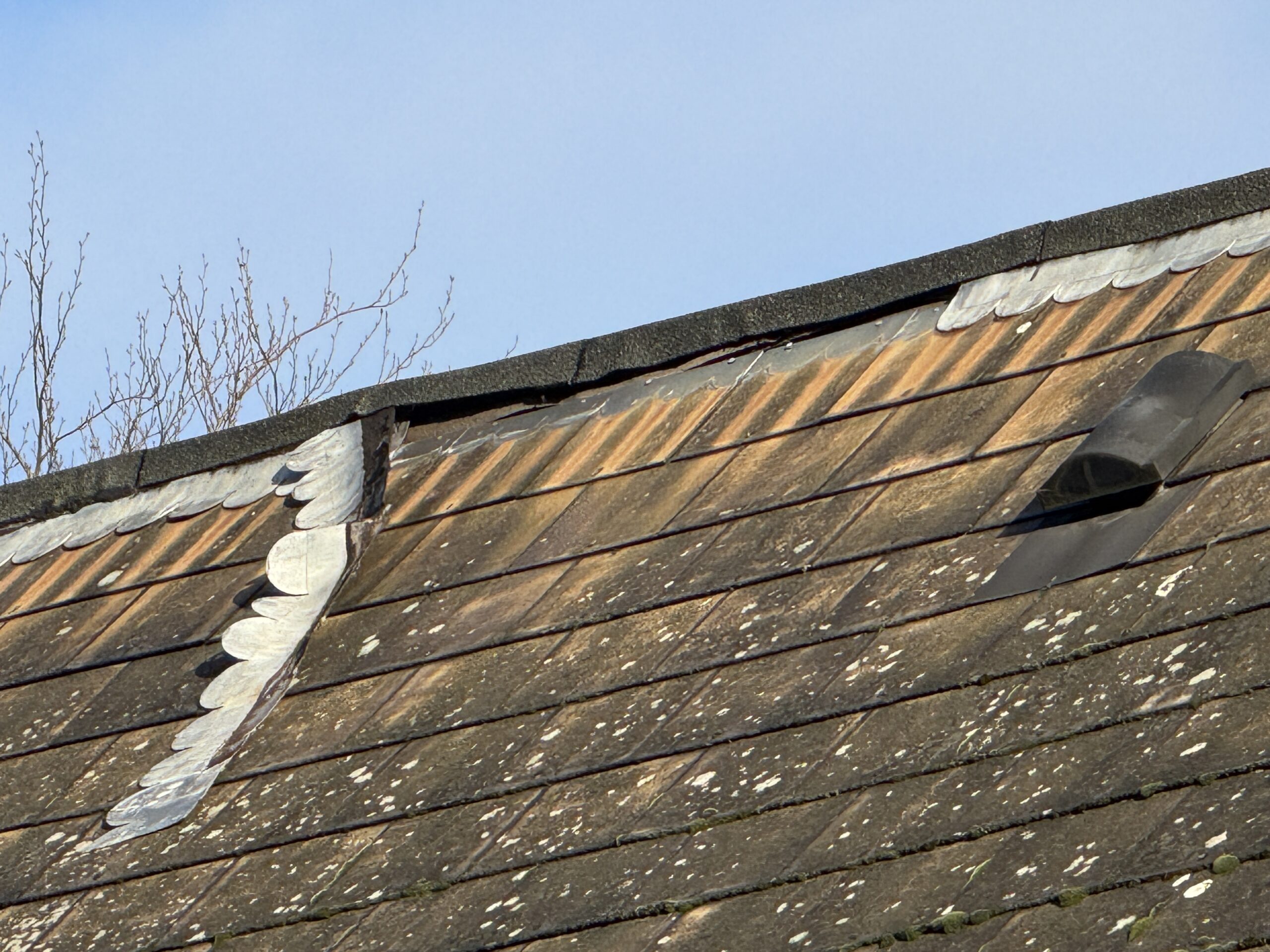 Close-up of deteriorating roof flashings and tiles